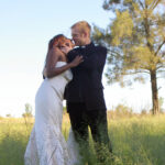 Bride and groom kiss in field
