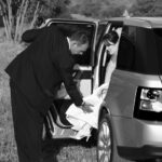 Groom helps bride back into car